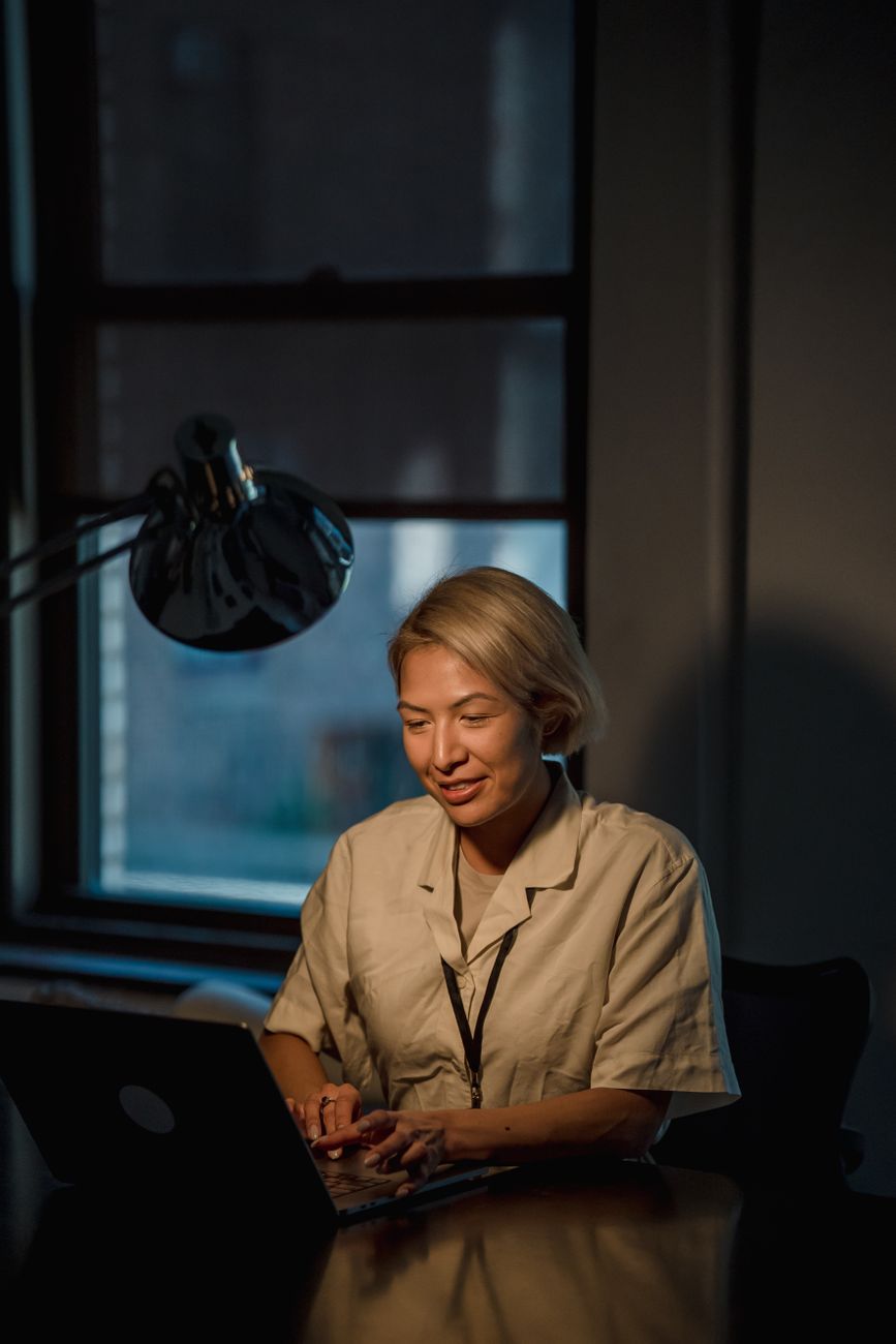 A woman working on a laptop in a dim room