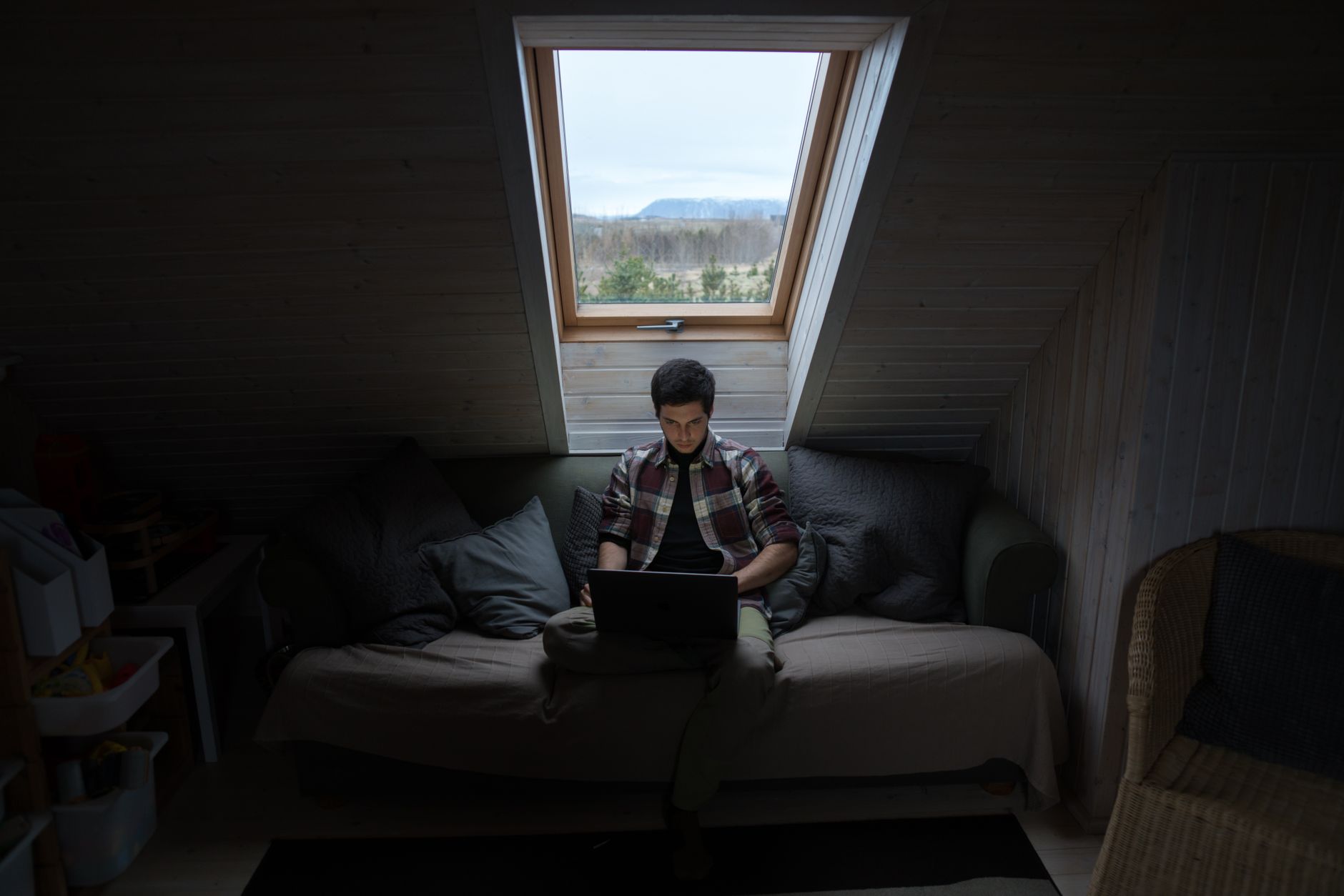 Person using a laptop in a room by a window